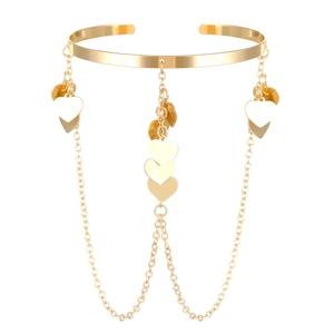 Detailed close-up of golden arm cuff featuring multilayer chains and heart charms