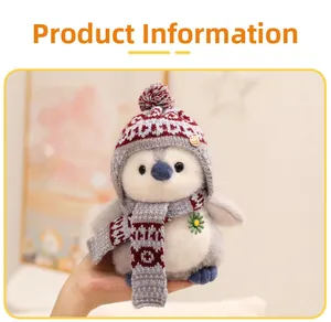 Detailed view of plush penguin doll with knitted hat and scarf being held by hand