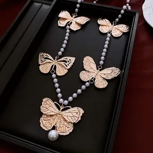 Vintage gold butterfly necklace with white pearls displayed on a black jewelry tray