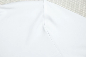 Gros plan des coutures invisibles et de la maille fine de cette robe chemise blanche