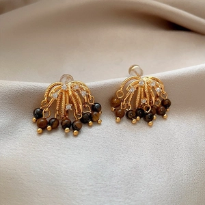 Sparkling zircon and tiger eye tassel earrings in gold on beige silk background