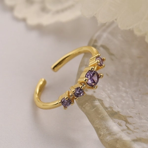 Elegant gold plated open ring with four purple zircon stones on a lace background