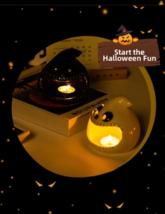 Close-up of black and white ceramic ghost candle holders with warm tea light glow