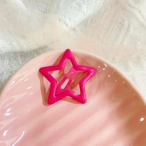 Detail of pink star-shaped snap hair clip on elegant lace background with shell tray