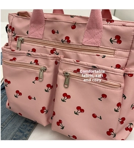 Detail of pink tote bag with cherry print showing multiple zipper pockets and fabric