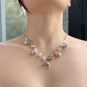 Close-up of summer beach necklace with silver dolphin pendant and pink starfish charms