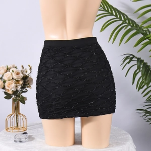 Détail de la mini-jupe noire présentant un tissu texturé ondulé et un éclat métallique subtil