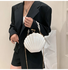 Detail of white shell-shaped handbag with golden chain strap and acrylic handle