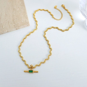 Golden wavy chain necklace featuring a rectangular green glass pendant on marble surface