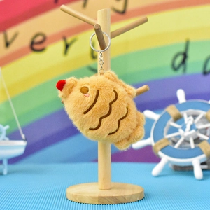 Detailed macro view of a cute brown plush croissant keychain on a wooden stand