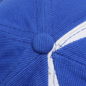 Macro shot of blue cotton baseball cap top button and detailed reinforced stitching