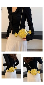 Detail of candy-shaped gold crossbody bag with a metallic chain and glossy finish
