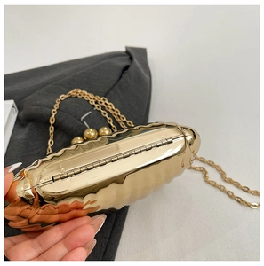 Close-up of gold wave patterned acrylic shell evening bag with metal chain strap