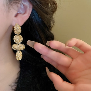 Close-up of vintage golden hammered metal teardrop earrings worn by a female model