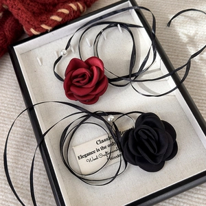 Detail of fabric rose choker necklaces in red and black with ribbons and pearls