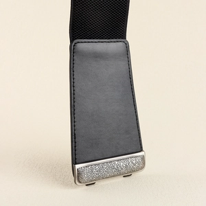 Detail of silver leopard-textured metal buckle and black leather on wide elastic belt