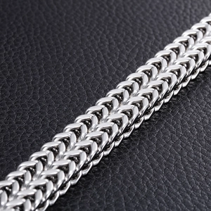 Macro shot of silver stainless steel dragon bone chain bracelet on black leather background