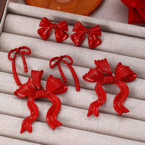 Close-up of three styles of red bow earrings displayed in a beige velvet jewelry box