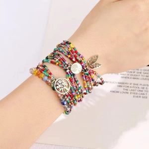 Detail of bohemian multilayer bead bracelet with golden Tree of Life and leaf charms