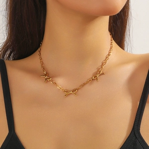 Detailed view of a gold-plated cross chain necklace with three elegant bow pendants on a model