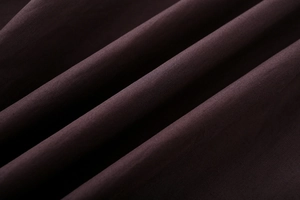 Macro detail of dark burgundy cotton poplin fabric showing soft pleated texture and weave
