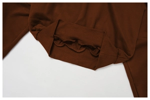 Detailed close-up of dark brown ribbed cuff with ruffled edge on oversized hoodie