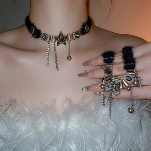 Detail of plush black choker with gold stars, cross pendants and metallic tassels