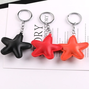 Close-up of star-shaped PU leather keychains in black, red, and orange with metal rings