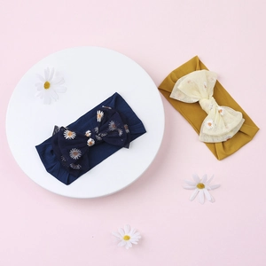 Detail of baby nylon headbands with embroidered daisy tulle bows in navy and mustard yellow