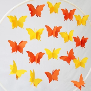 Detail of 3D paper butterfly hanging ornaments in yellow and orange on a white frame