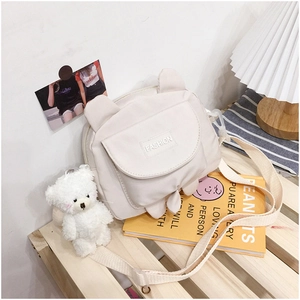 Close-up of a cream canvas crossbody bag with cute bear ears and adjustable strap detail