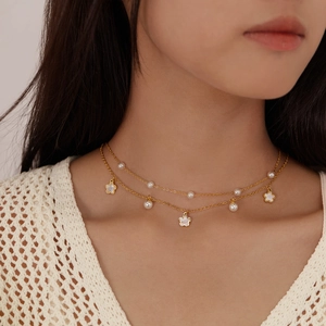 Double-layered gold stainless steel necklace with white flower charms and elegant pearls