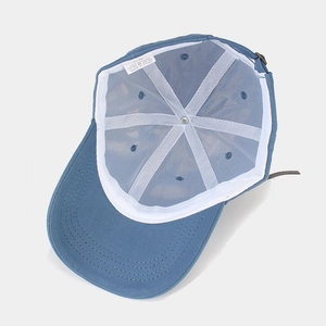 Interior view of a blue cotton baseball cap showing white support tape and washing label