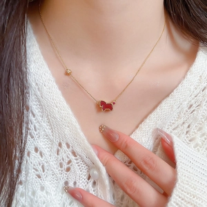 Gros plan d'un collier doré avec pendentif animal rouge et bords perlés sur un mannequin
