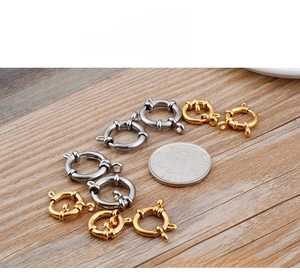 Gold and silver round spring clasps size comparison with a coin on a wood background