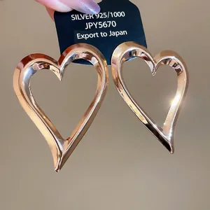 Minimalist heart shaped rose gold dangle earrings with polished mirror finish on black card