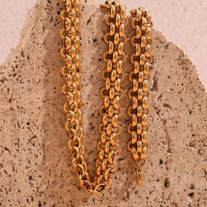 Detailed close-up of 18K gold plated multi-link chain on textured brown stone base