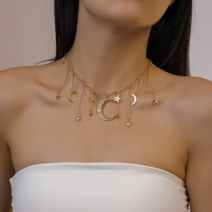 Gros plan du collier à pompons dorés avec croissant de lune serti et perles fantaisie