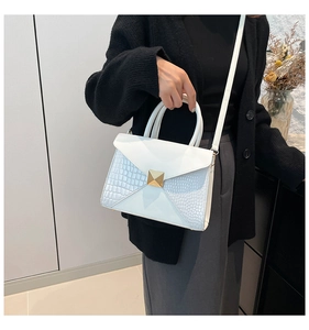 Detail of white crocodile pattern stitching and golden square metal buckle on handbag