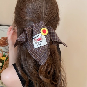 Detail of checkered bow hair clip with vintage button on a woman wavy hair