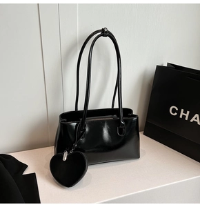 Detail of black patent leather shoulder bag with matching heart-shaped coin purse accessory