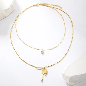 Close-up of gold double-layer necklace with butterfly pendant and safety pin detail