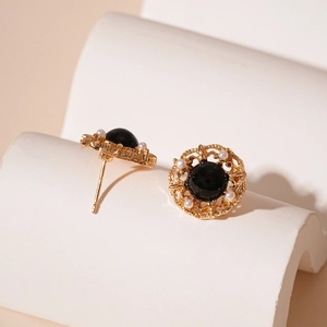Gros plan de boucles d'oreilles dorées vintage avec pierre noire et perles