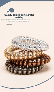 Close-up of metallic spiral telephone wire hair ties in gold, silver, and bronze colors