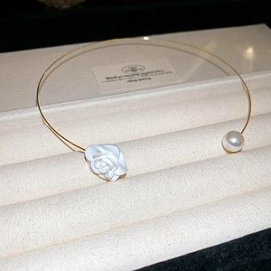 Detailed shot of gold open choker featuring a white rose flower and a pearl accent