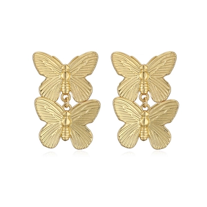 Detailed close-up of golden double butterfly stud earrings with polished metallic finish