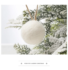 Close-up of a white wool felt ball ornament hanging on a snowy Christmas tree branch