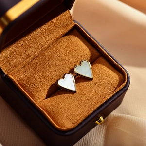 Macro shot of gold-plated heart earrings with white mother-of-pearl in a gift box