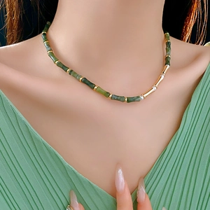 Close-up of bamboo pearl necklace with green beads and gold accents on a model