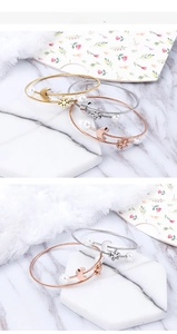Detailed view of woven steel bracelets with moon, snowflake, and pearl charms